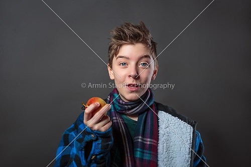 funny teenage boy holding an apple, isolated on gray background