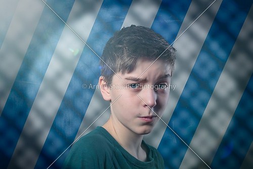 portrait of a doubting teenage boy with flare, striped backgroun