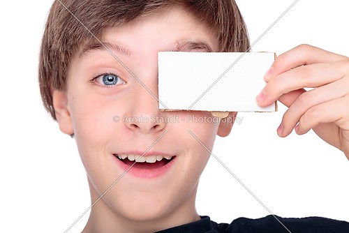 portrait of a smiling teenager boy holding a white piece of card