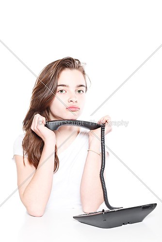 sulking female teenager holding telephone receiver in both hands