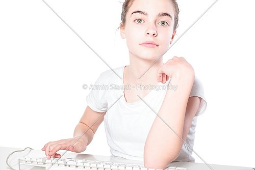 smiling teenager girl working on a keyboard, isolated on white