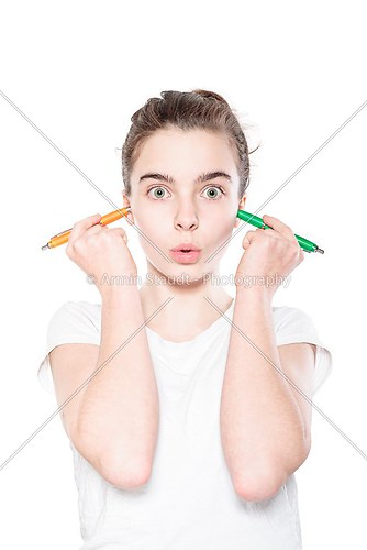 funny teenager girl holding to pens in her ears, isolated on whi