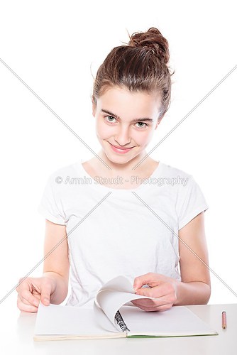 sitting female teenager browsing in an open empty book, isolated