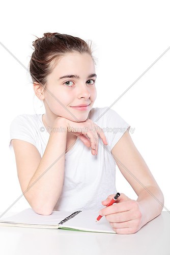 smiling female teenager with blank note book sitting at a table,