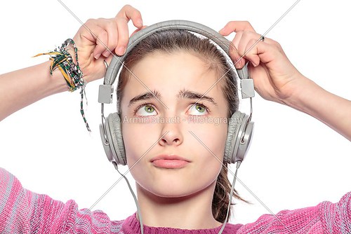 beautiful teenager girl fumble on her headphones, isolated on wh