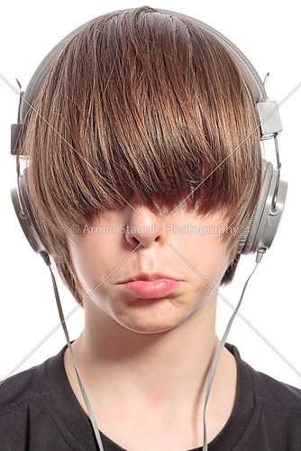 sulking cute teenager boy with hair over his eyes and headphones