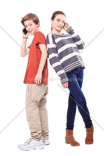two smiling teenager, back on back with their mobile phones, iso