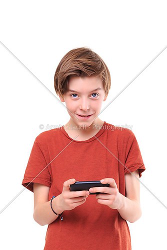 smiling male teenager with smart phone in both hands, isolated o