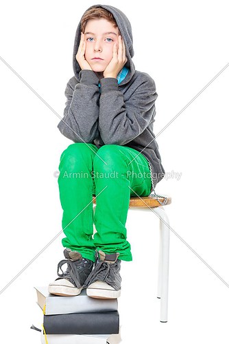 teenager boy sitting on a stool with his feet on a stack of book