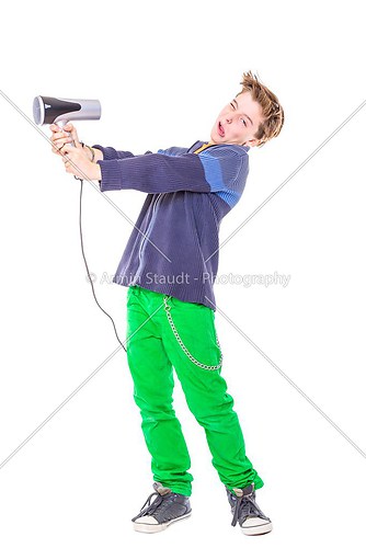 casual teenage boy is fighting with a hair dryer, isolated on wh