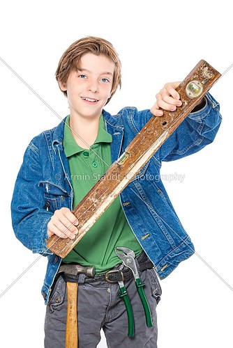smiling boy with tool in his belt holding a water level in his h