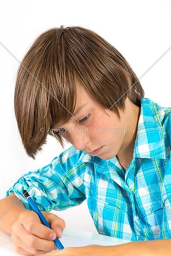school boy with pencil works concentrated, isolated on white