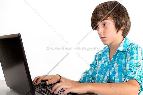 school boy working on a laptop, isolated on white