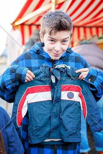 funny teenage boy on a flea market is trying too small dresses 