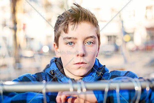portrait of a teenage boy behind a clothes rail on a flea market