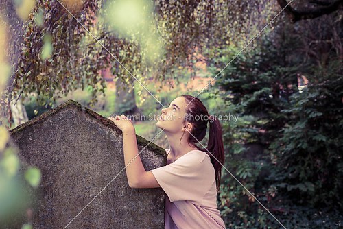 vintage shoot of a woman touching a moss overgrown tombstone