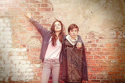 siblings in front of an old grungy brick wall