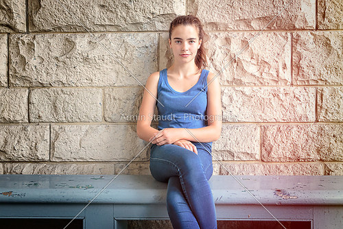 portrait of a beautiful teenage girl sitting on a wooden bench