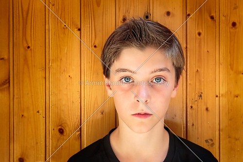 portrait of a beautiful teenage boy in front of a wood plank wal