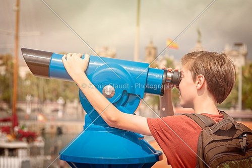 teenage boy with rucksack looking through a sightseeing monocula