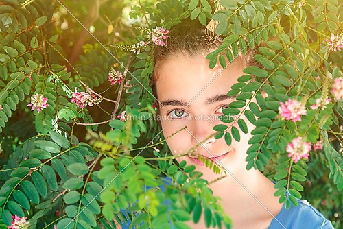 portrait of a beautiful teenage girl in a blooming bush