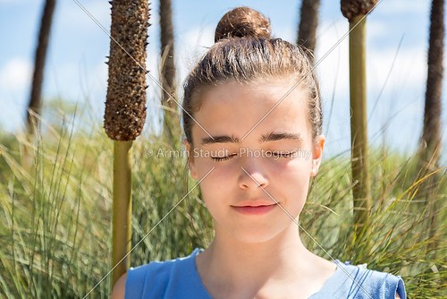 teenager girl meditates in front of a reed field