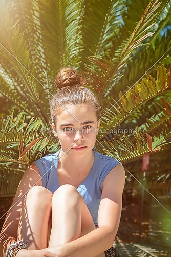 portrait of a teenager girl, sitting in front of a palm tree