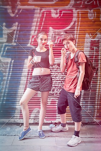 two teenager eating ice cream in front of a graffiti shutter