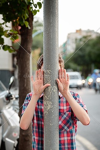 boy with hands up behind a lamppost