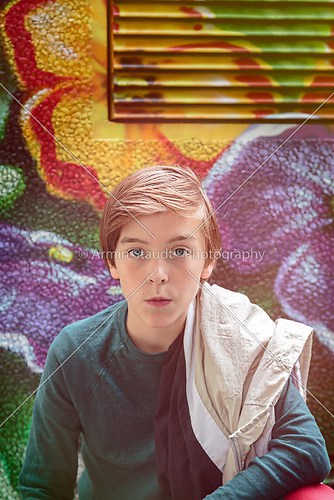 beautiful teenager boy kneeing in front of a flower graffiti