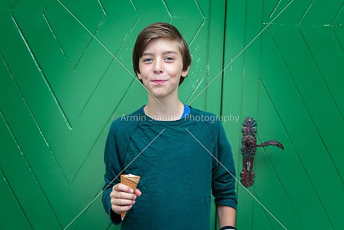 lucky teenager boy with ice cream cone in front of a green door