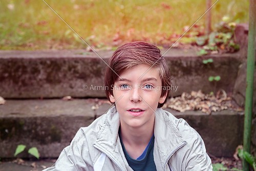 smiling teenager boy sitting on stairs in a park