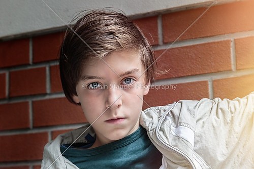 portrait of a cool teenager boy in front of a brick wall