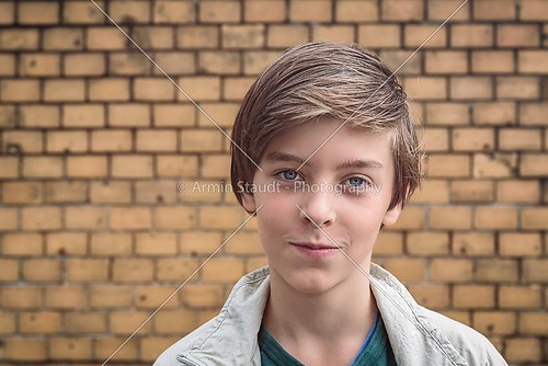 portrait of a smiling male teenager in front of a yellow brick w