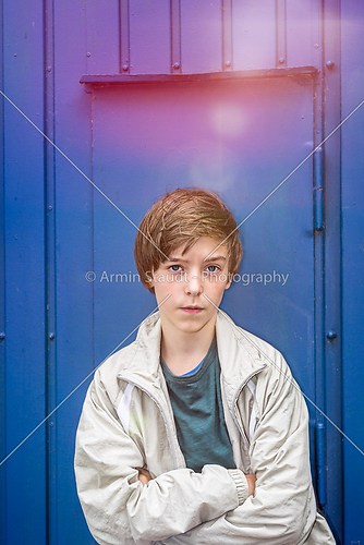 portrait of a teenager boy in front of a blue wall