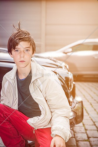 portrait of a teenager boy in front of a old expensive car