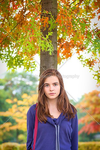 portrait of a female teenager standing under a autumn tree