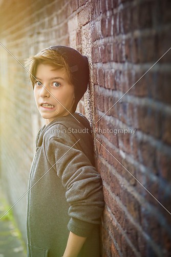terrified teenager boy leaning on a wall