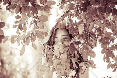 vintage like portrait of a female teenager behind some leafs