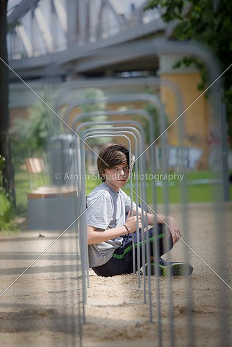 portrait of a teenager boy sitting behind a metal frame