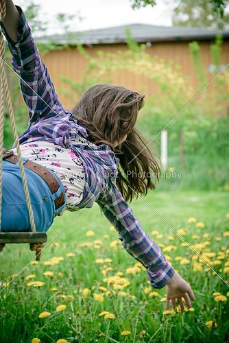 girl on a swing stretching here arm to a meadow