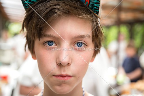 young boy with basecap looking into the camera, blurred people i