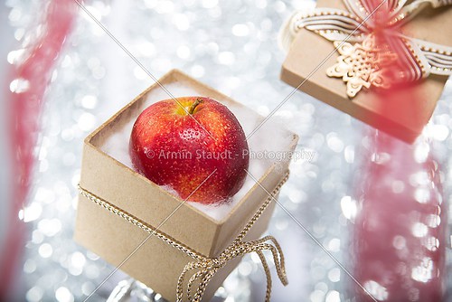 open christmas gift box with an apple, ribbon and bow