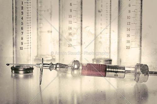 vintage syringe with blood and empty glass syringes in backgroun