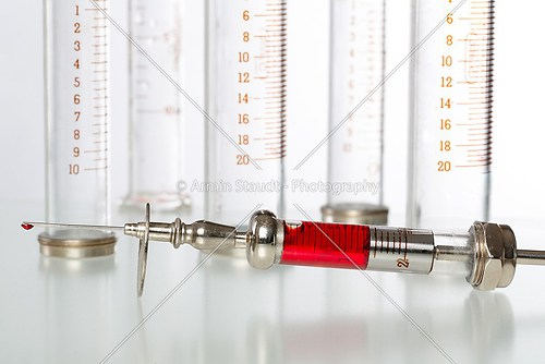 syringe with blood and empty glass syringes in background