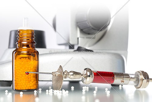 still life with homeopathy globules, syringe with blood and micr