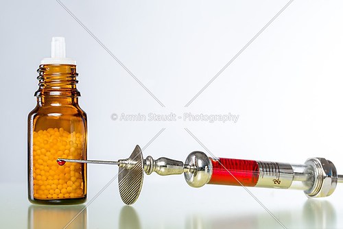 still life with homeopathy globules and syringe with blood