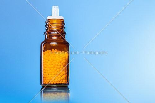 single bottle with homeopathy globules with blue background