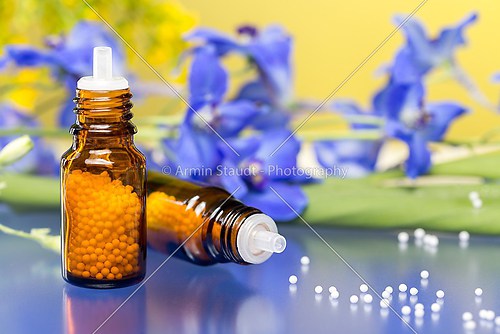 two bottles with homeopathy globules and flowers, with blue refl