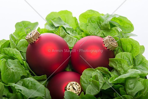 fresh green salad with three red christmas ball&#039;s, isolated on w